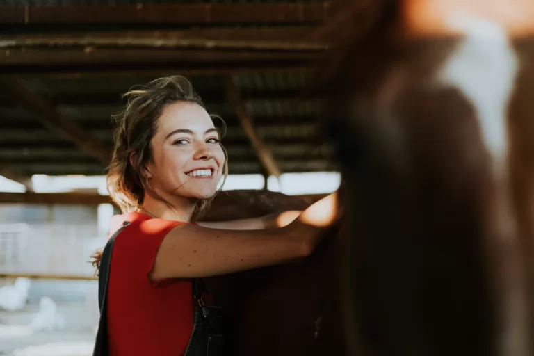 Une femme rayonnante partageant une connexion unique avec son noble compagnon équin, illustrant la symbiose entre l'huile CBD et le bien-être équin.